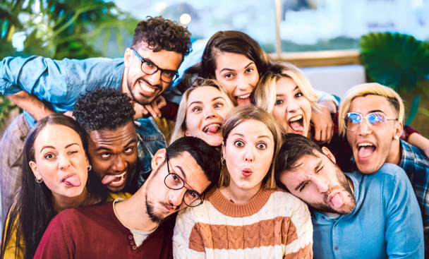 Wielokulturowi mężczyźni i kobiety biorący selfie wystające z języka z szalonymi śmiesznymi twarzami - koncepcja stylu życia i integracji z młodymi przyjaciółmi o wspólnej zabawie - Filtr światła wewnątrz - Zdjęcie, obraz