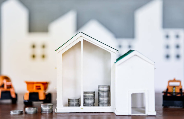 Miniature house models and construction truck models with glod coin on wooden table. Real estate developement or property investment. Construction industry business concept. - Photo, Image