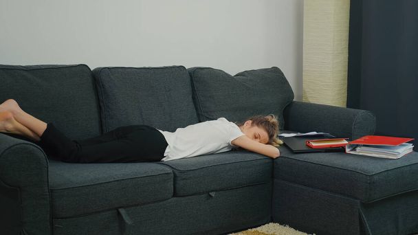 Pierwsze doświadczenie zawodowe. Młoda kobieta spała na kanapie obok laptopa i dokumentów biurowych po ciężkim dniu pracy. Przepracowana praca w domu. Pierwsza praca po studiach i wiele nowych rzeczy do nauczenia się. - Zdjęcie, obraz