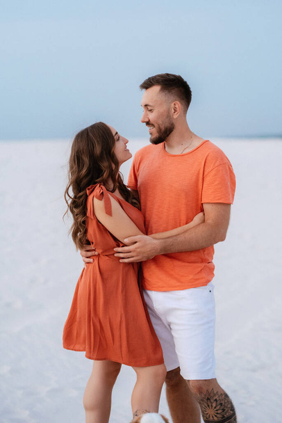 young couple in orange clothes with dog in the desert white sands - Foto, Imagem