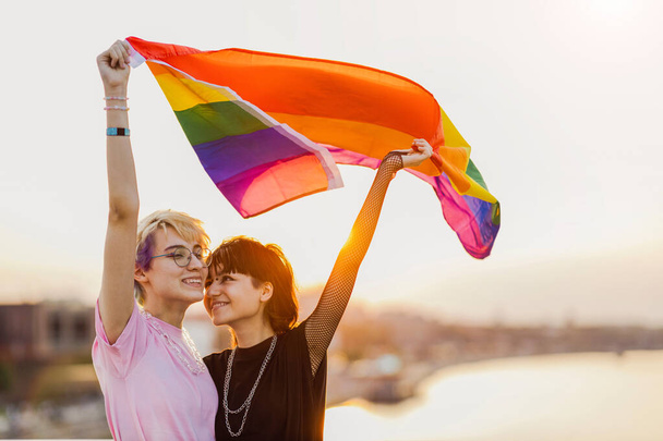 Portrait of happy non binary couple waving rainbow flag - Valokuva, kuva