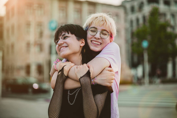 Young gender fluid couple hugging on city street - Foto, afbeelding
