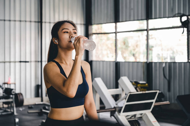 Азиатская молодая женщина питьевой воды после тренировки в тренажерном зале, исцеления и спортивной концепции. - Фото, изображение