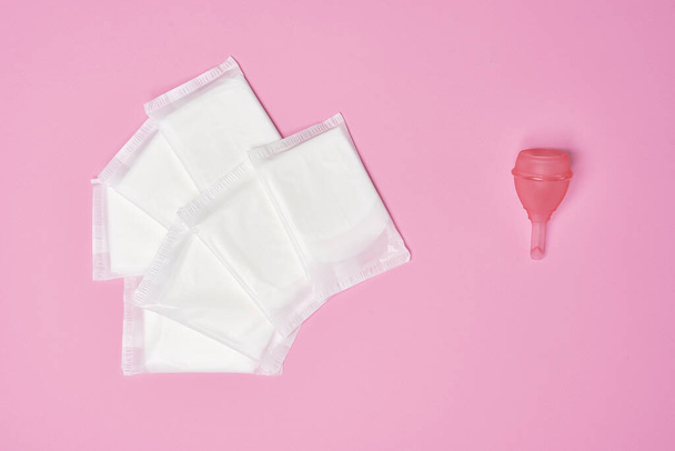packaged cotton sanitary napkin pad, silicone pink menstrual cup on pink background - Photo, image