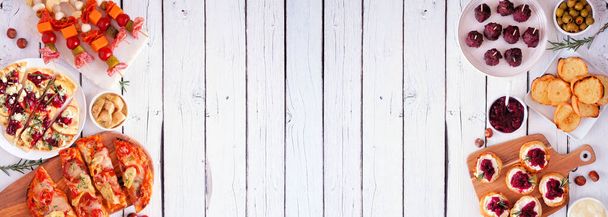 冬休みのテーマ前菜。白い木のバナーの背景に二重の境界線を表示上。フラットブレッド、串焼き、クランベリークロスティーニ、各種パーティーフード。スペースのコピー. - 写真・画像