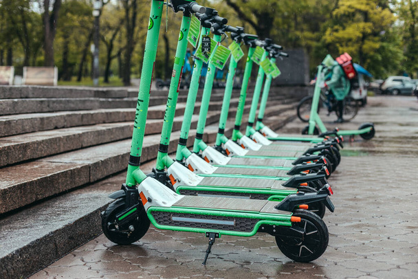 Row of mint rental motorized kick scooters in the center of rainy city. Electric Urban transportation concept. - Photo, Image