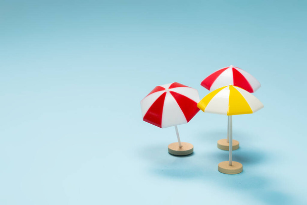 Żółto-czerwony parasol na niebieskim tle. Przestrzeń kopiowania. - Zdjęcie, obraz