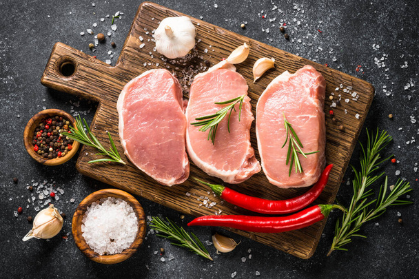 Steaks de porc frais sur planche à découper avec ingrédients pour la cuisson. - Photo, image