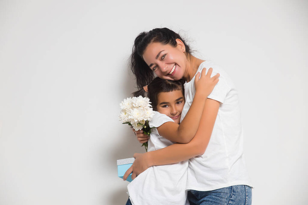 Cute child girl congratulating loving mum, giving bouquet of white flowers, gift box. Womens or Mothers Day - Φωτογραφία, εικόνα