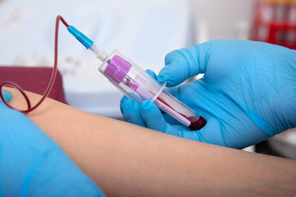 laboratory assistant draws blood from a patient's vein with a disposable syringe. concept is test for covid in medical institution. - Fotoğraf, Görsel
