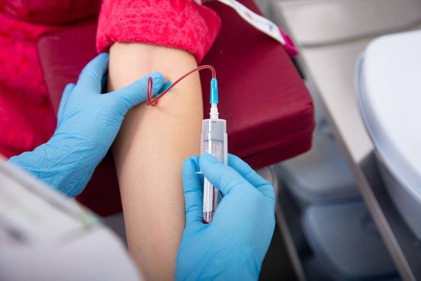laboratory assistant draws blood from a patient's vein with a disposable syringe. concept is test for covid in medical institution. - Foto, Imagen