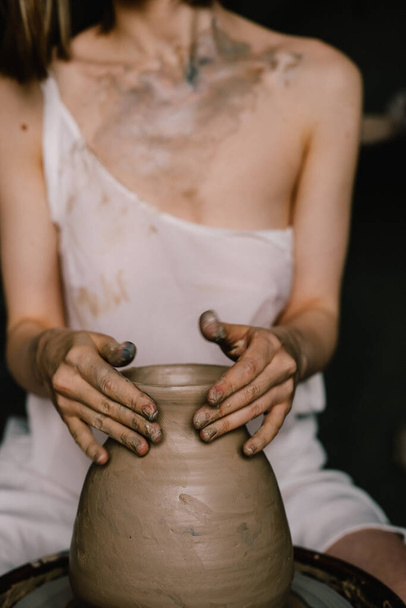 young girl in a white shirt makes a pitcher of clay on a potter's wheel. Pottery workshop of a creative woman. Concept - hobby clay - Foto, immagini