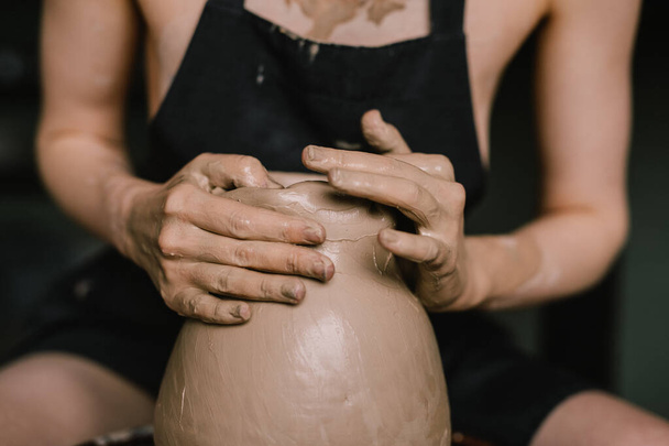 young girl in black apron on her naked body sculpts a jug of clay on a potter's wheel. Pottery workshop of a beautiful woman. Concept - hobby pottery production - Foto, Bild