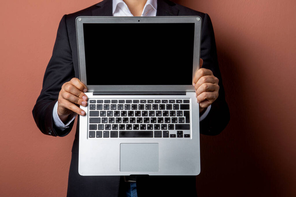 businessman man in a black jacket holds an open silver laptop in his hands. Technologies in financial sphere. Concept - Digital era - Foto, imagen