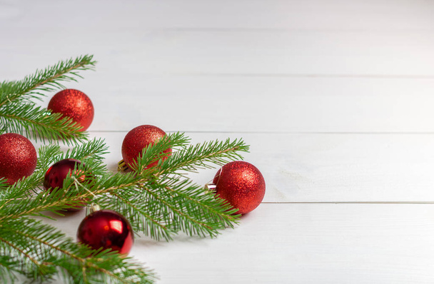 Υποκαταστήματα χριστουγεννιάτικου δέντρου και χριστουγεννιάτικο κόκκινο χριστουγεννιάτικο στολίδι σε λευκό ξύλινο φόντο. Αντιγραφή χώρου. - Φωτογραφία, εικόνα