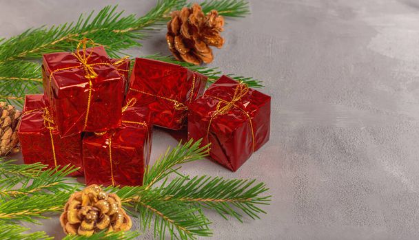 枝とクリスマスツリーのコーンの間の贈り物と赤い箱。コピースペース。クリスマスのコンセプト. - 写真・画像