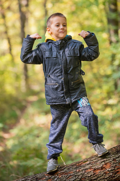 Молодий хлопчик стоїть на фоні сліду дерева і ловить рівновагу - Фото, зображення