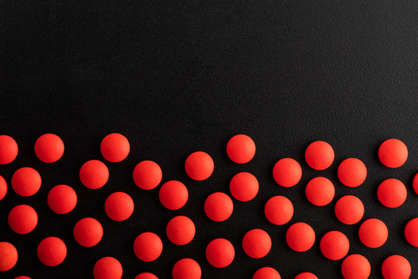 Red pills on a black background with place for text. Medicine, healthcare concept. Range of pharmaceutical drugs - Foto, Imagen