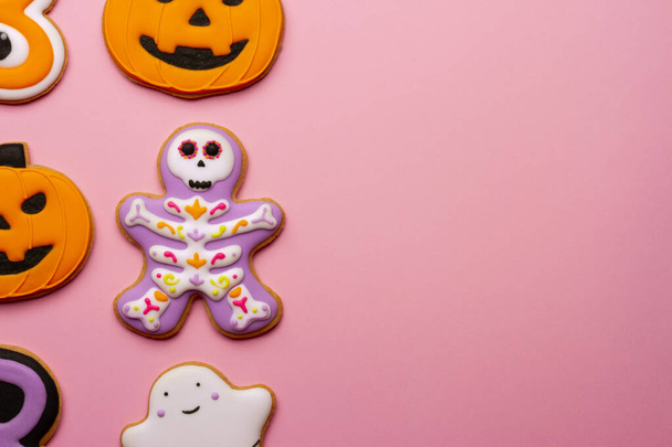 Σπιτικά αποκριάτικα μπισκότα, κολοκύθες, φαντάσματα, σκελετοί σε ροζ φόντο. - Φωτογραφία, εικόνα