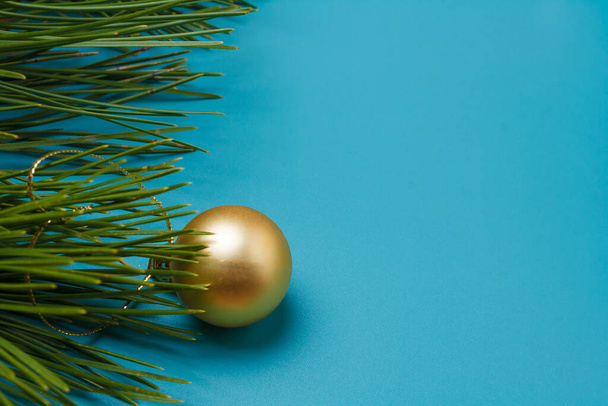 Merry Christmas, Happy New Year postcard, template. Blue background, pine tree branches, golden bauble. Close up shot, copy space - Photo, Image