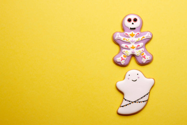 Zelfgemaakte koekjes schattige skeletten en spoken voor Halloween op gele achtergrond. - Foto, afbeelding