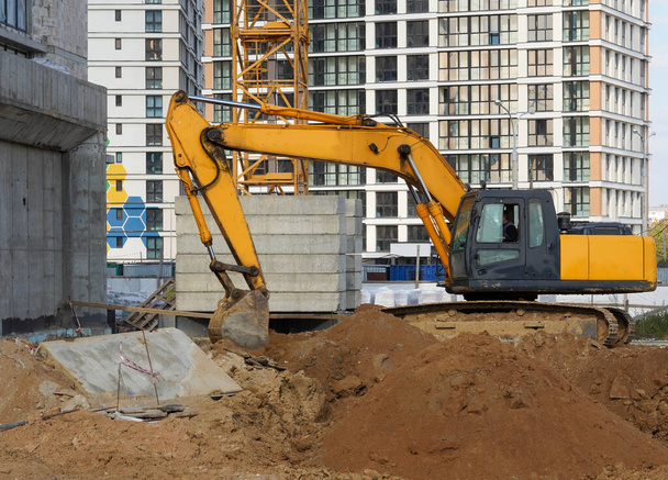 Photo of a construction site of multi-storey buildings and yellow excavator in the city. - Foto, Imagen