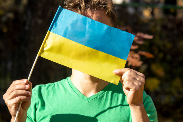 Μικρή κίτρινη και μπλε σημαία της Ουκρανίας στα χέρια - Φωτογραφία, εικόνα