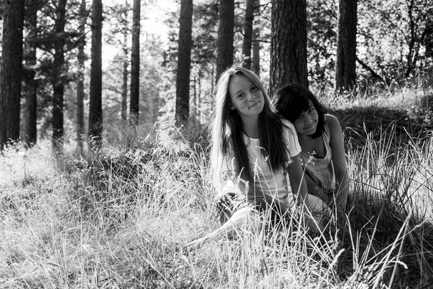 Deux amies adolescentes sur l'herbe dans un parc d'été. Photo noir et blanc. - Photo, image