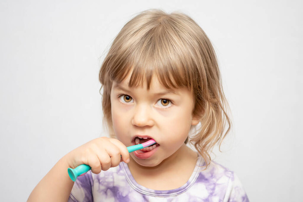 Una bambina si sta lavando i denti. Una ragazza con uno spazzolino da denti. Igiene orale - Foto, immagini