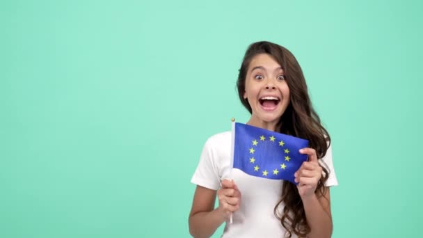 bambino sorpreso sventola bandiera sindacale europea su sfondo blu mostrando pollice in su, visto schengen - Filmati, video
