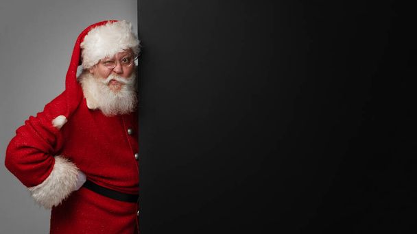 Santa Claus holding black banner with copy space for text - Fotó, kép