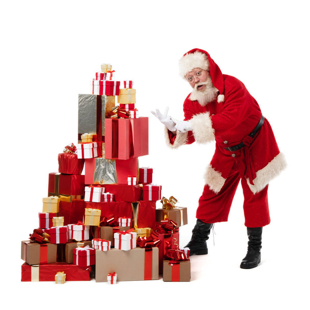 Santa Claus dancing near large pile of Christmas gifts isolated on white background - Photo, Image