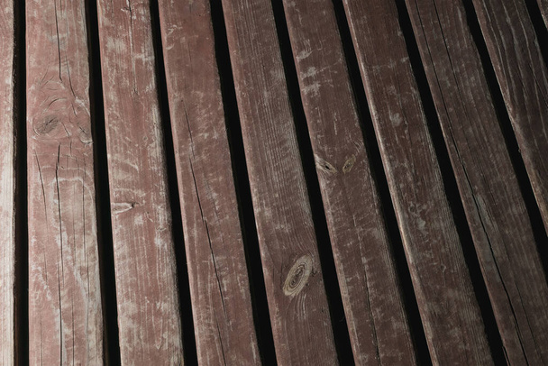 Wooden platform with cracked paint, made of planks in the dark - Fotoğraf, Görsel