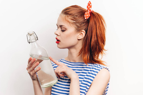 beautiful woman in striped t-shirt with bottle of alcohol light background - Fotoğraf, Görsel