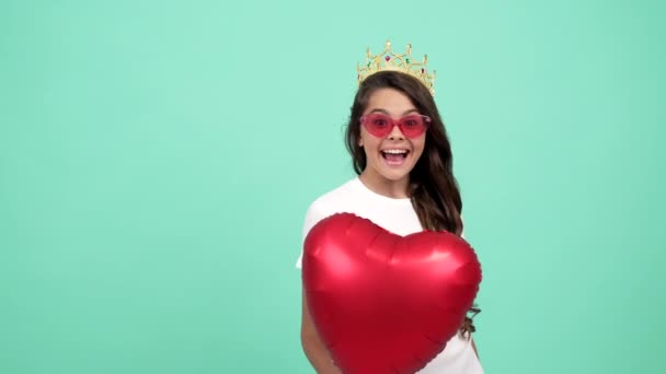 portret szczęśliwej nastolatki w okularach przeciwsłonecznych i korony trzymać serce strony balon, sen - Materiał filmowy, wideo