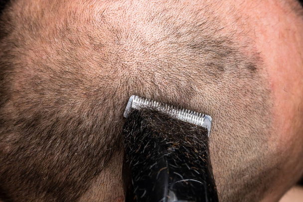 Mężczyzna golenie lub przycinanie włosów za pomocą strzyżenia - Zdjęcie, obraz