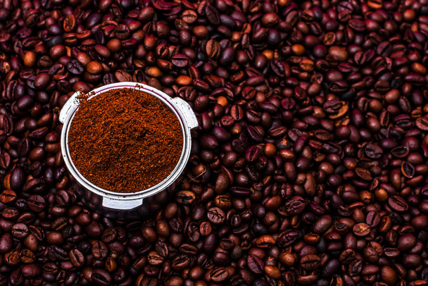 Background with ground coffee in portafilter surrounded by roasted coffee beans, - Photo, Image