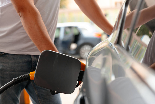 Hand Man ξαναγεμίστε και γεμίστε το πετρέλαιο καύσιμο φυσικό αέριο στο σταθμό. Για να γεμίσει το μηχάνημα με καύσιμα. Αυτοκίνητο γεμάτο βενζίνη σε βενζινάδικο. Αντλία βενζίνης. - Φωτογραφία, εικόνα