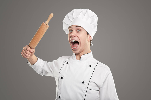 Crazy male chef raising rolling pin and screaming - Фото, изображение