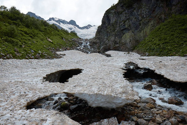 krajobraz górski, topniejący śnieg, lodowiec i potok górski, jaskinie w lodzie - Zdjęcie, obraz