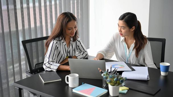 Two of businesswomen in marketing team discuss and create new marketing campaign together, sits in a modern workplace. - Photo, image