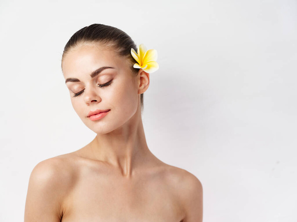 гарна жінка з голими плечима закритими очима чарівна квітка у волоссі
 - Фото, зображення