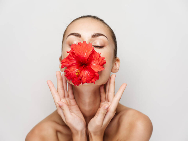Frau mit geschlossenen Augen Blume Mund nackte Schultern isoliert Hintergrund - Foto, Bild