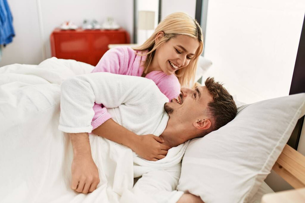Nuori valkoihoinen pari hymyilee onnellisena ja halaa sängyssä kotona. - Valokuva, kuva