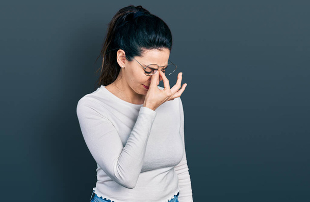 Young hispanic woman wearing casual clothes tired rubbing nose and eyes feeling fatigue and headache. stress and frustration concept.  - Photo, Image