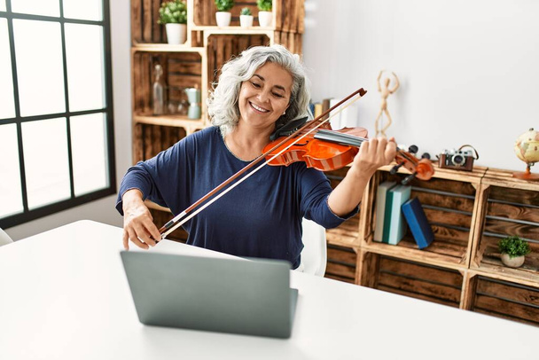 Középkorú ősz hajú nő játszik online hegedű koncert a rádióban stúdió. - Fotó, kép