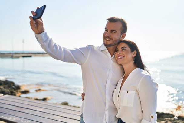 Hombre y mujer pareja abrazándose hacer selfie por el teléfono inteligente de pie en la playa - Foto, Imagen