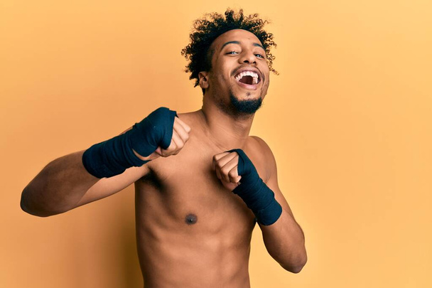 Молодий афроамериканець з бородою в боксерському захисті посміхається і сміється голосно, тому що смішний божевільний жарт.  - Фото, зображення