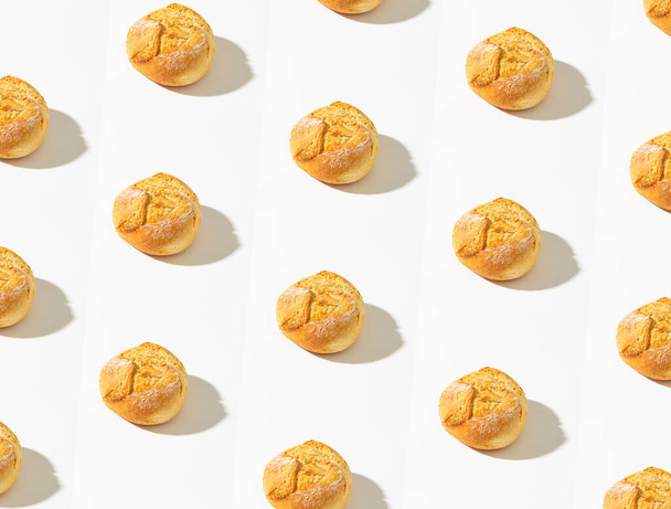 Pattern made with Crusty round bread rolls, known as Kaiser or Vienna rolls on white background - Fotó, kép