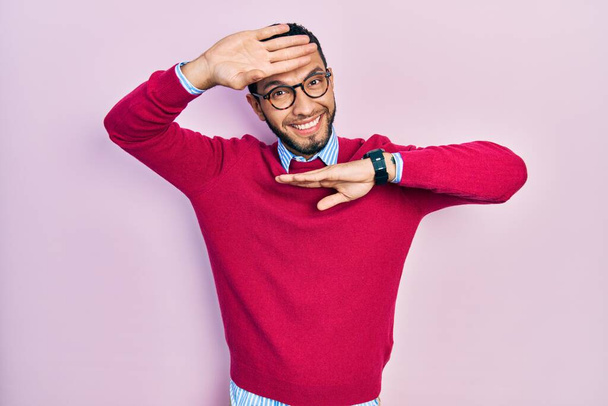 Hombre hispano con barba vistiendo camisa de negocios y gafas sonriente alegre jugando a echar un vistazo a un boo con las manos mostrando la cara. sorprendido y salido  - Foto, Imagen